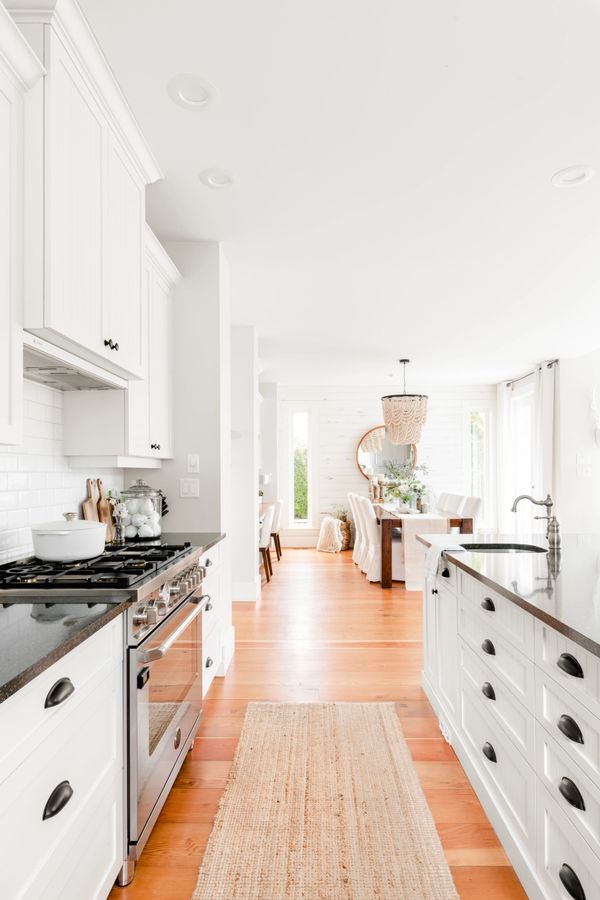 interior design open concept white kitchen with reclaimed fir floors and stainless gas range 