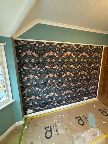 Feature wall decorating project with precision wallpaper installation, clean edges, and freshly pain