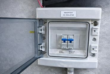 Electrical panel with two blue switches labeled grid and backup supply.