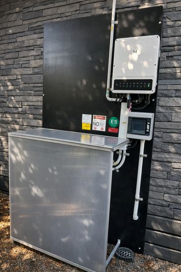 Modern electrical or solar power equipment mounted on a stone wall outdoors.