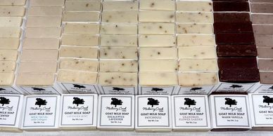 Rows of handmade goat milk soaps in various colors and scents.