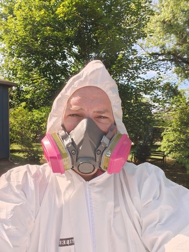 An inspector in full PPE before entering a tight crawlspace to do an inspection.