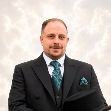 Man in a formal black suit with a teal paisley tie and pocket square.