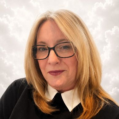 Woman with blonde hair and glasses against a cloudy background.
