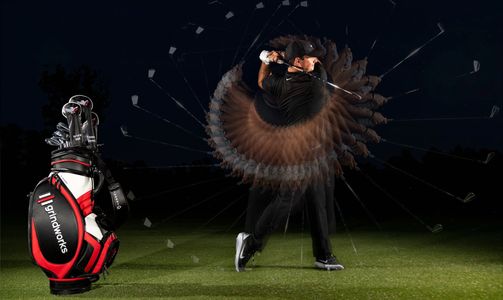 Patrick Reed mid-swing with motion effect, Grindworks golf bag in foreground on a night-lit course.