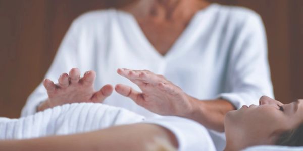 Hands performing energy healing over a person's body.