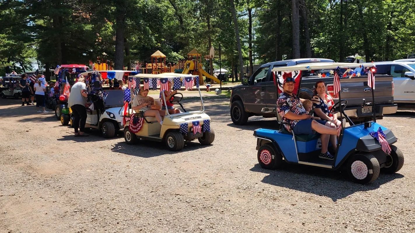 Patriotic golf carts decorated for a festive parade on a sunny day.