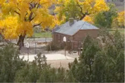 A rustic brick building surrounded by autumn trees and greenery.