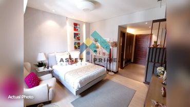 Modern bedroom with cozy bed, armchair, and warm lighting.