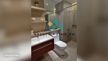 Modern bathroom with wooden vanity, white toilet, and tiled shower area.