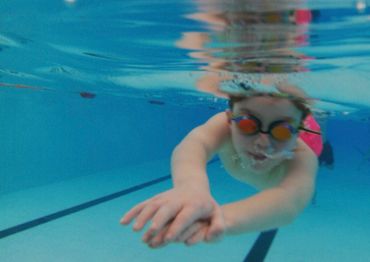 Young swimmer underwater wearing goggles in a pool.