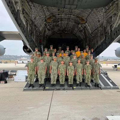 Group of military personnel posing in front of a cargo plane.