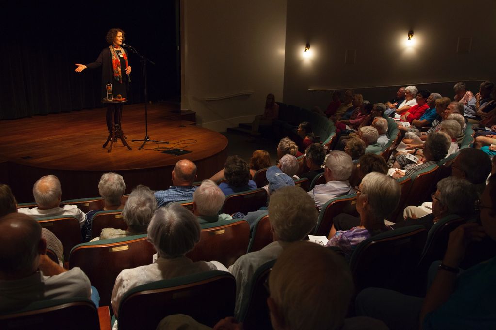 Ingrid stands on stage facing the audience.