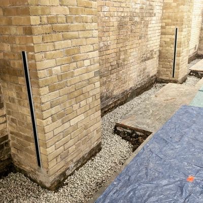 Interior basement trench beside a brick foundation wall in Toronto during waterproofing with gravel