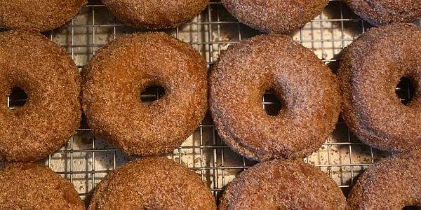 Apple cider donuts on a tray with cinnamon sugar.