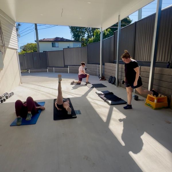 Four people exercising in a covered outdoor space.