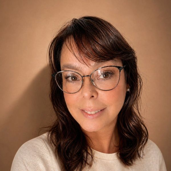 Smiling woman with glasses and wavy hair.