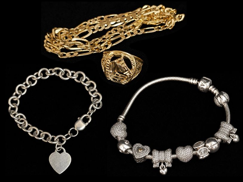 Jewelry collection comprising two silver charm bracelets, a gold chain, and a gold ring.
