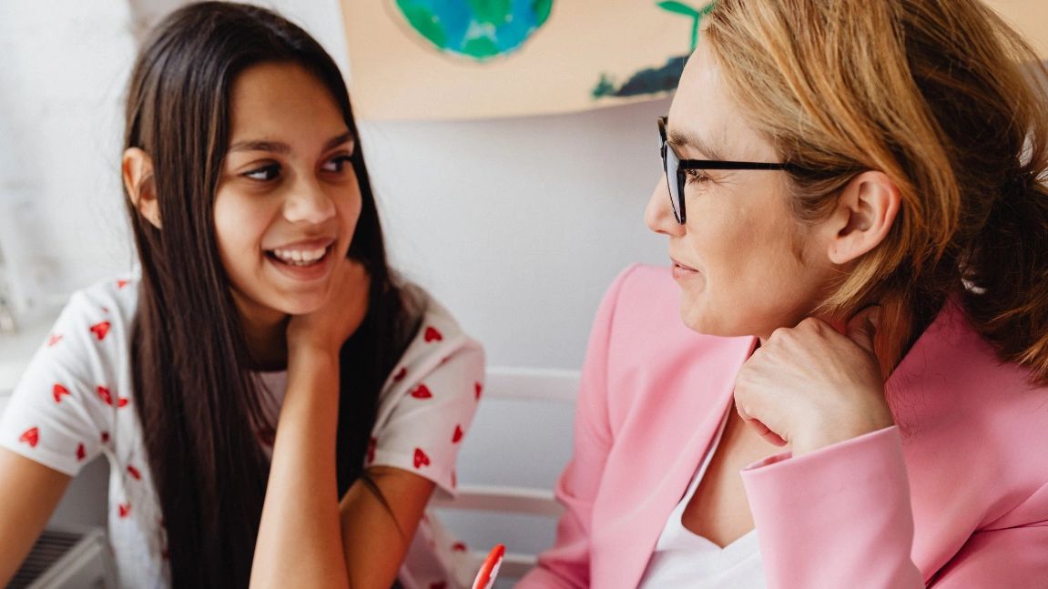 A Thrive Community Hub teacher talking to a young girl during a lesson