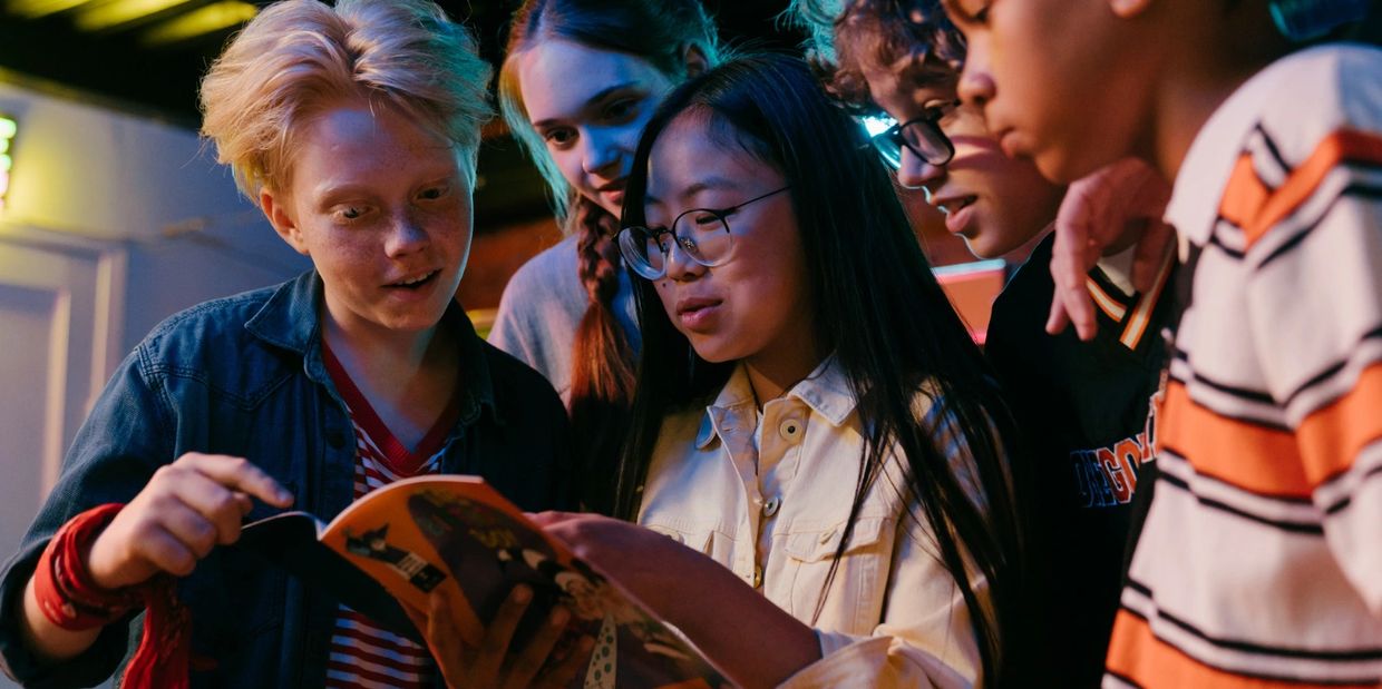 A group of children at Thrive Community Hub centre engaged in reading a colourful book