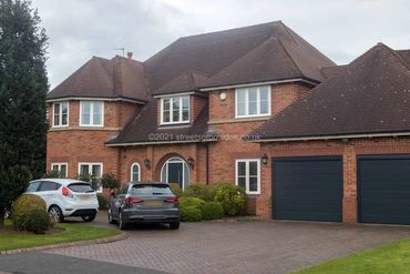 Large, detached home with double garage and two cars on the drive