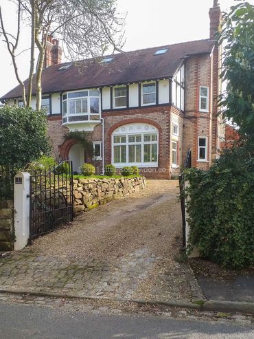 Large detached property at top of short drive behind open iron gates
