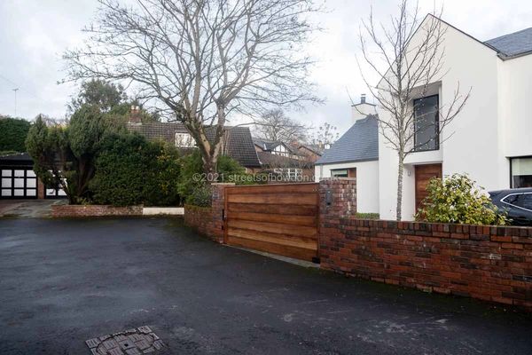 White house with another property hidden by a tree and shrubs