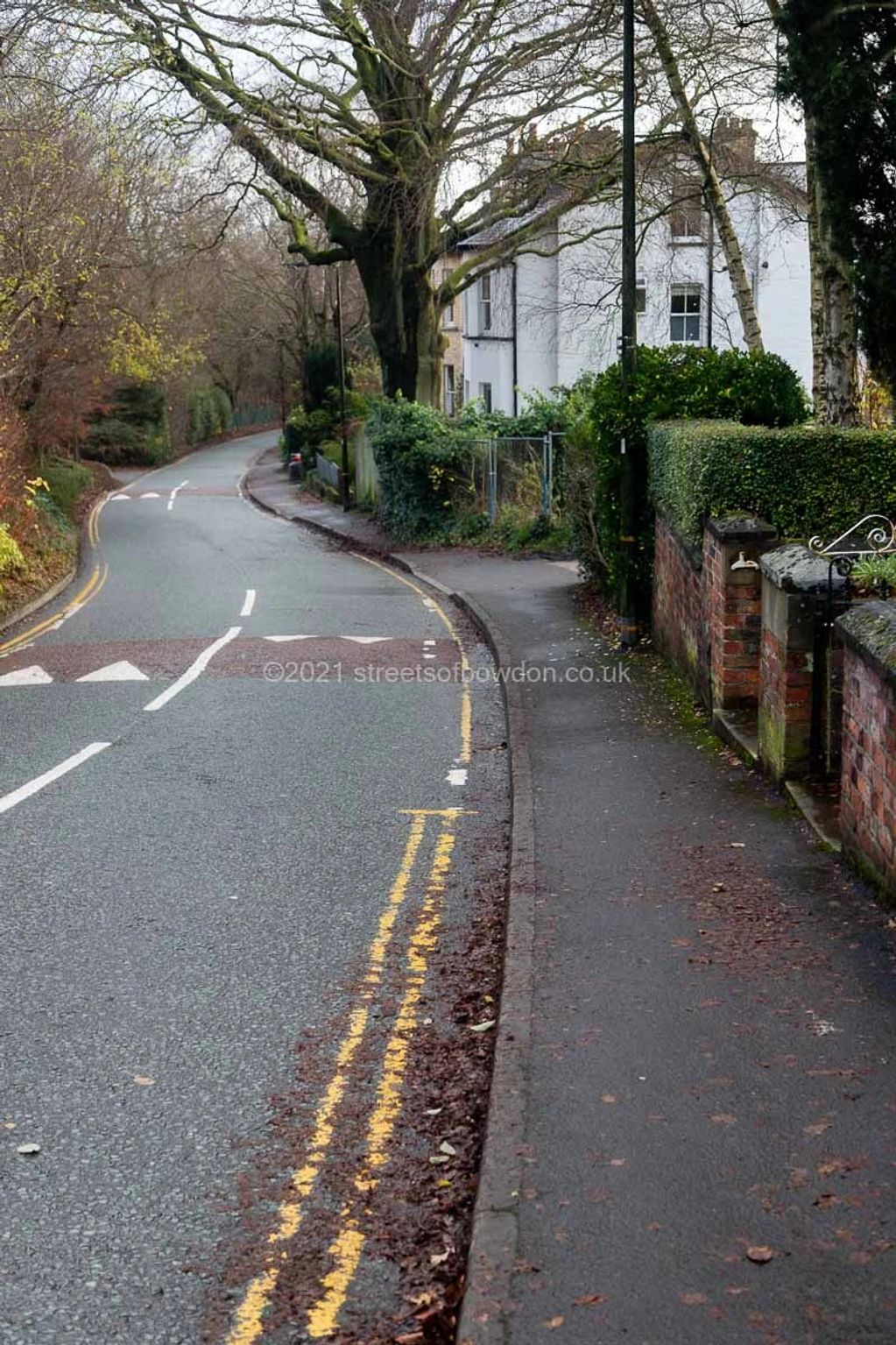 Road leading downhill past white-rendered property