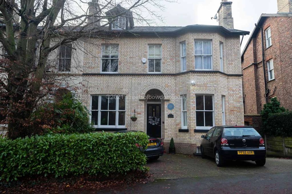 House with blue plaque and parked cars