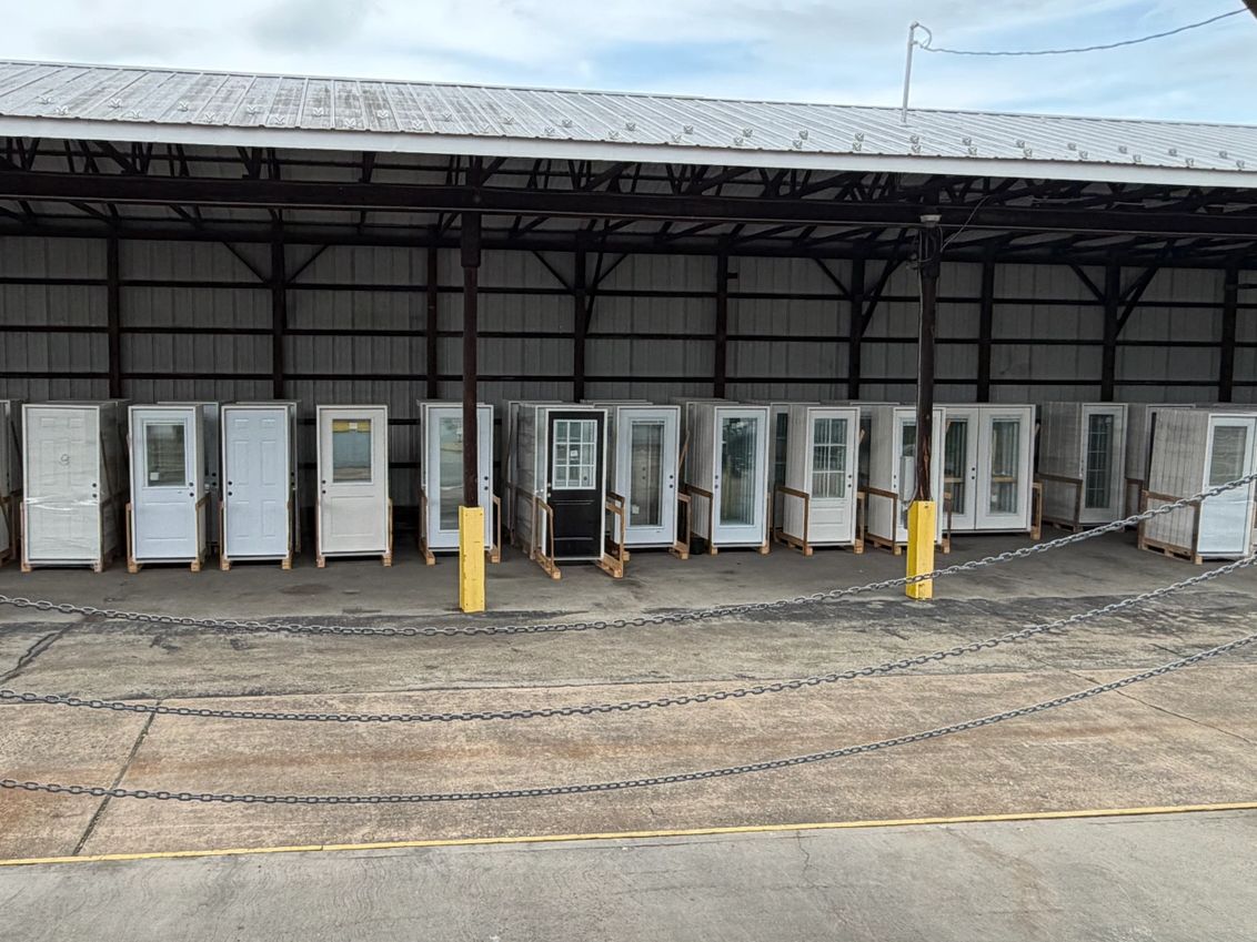 Rows of white and glass doors lined up under a metal roof.