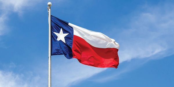 Texas state flag waving against a clear blue sky.