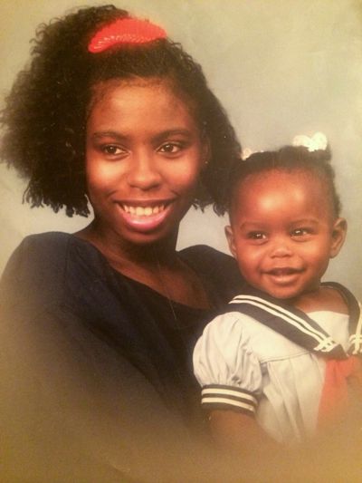 Smiling woman holding a happy toddler dressed in a sailor outfit.