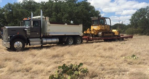 A large truck towing a trailer with a yellow bulldozer.