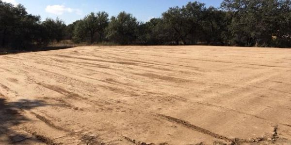 A cleared, flat dirt area surrounded by trees.