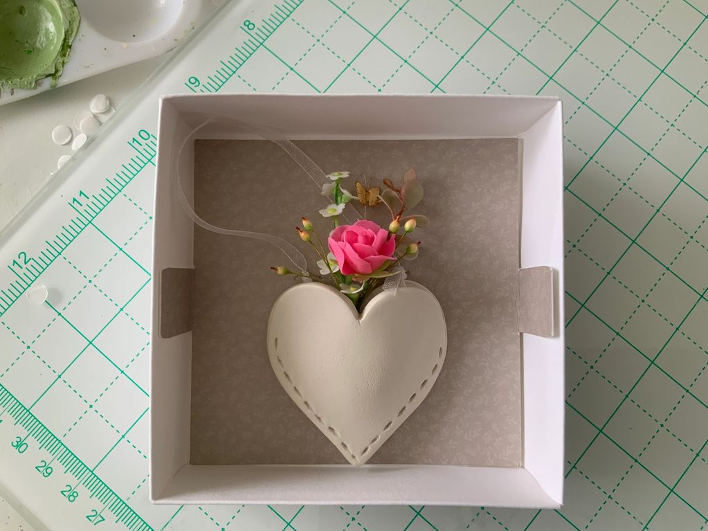 Heart-shaped ornament with flowers in a white box.