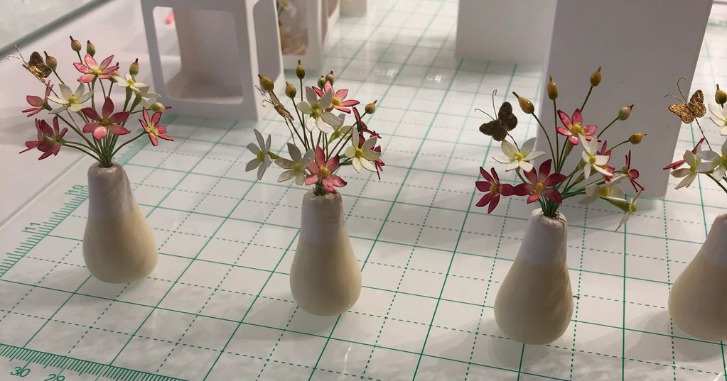 Miniature flower bouquets in small vases on a grid mat.
