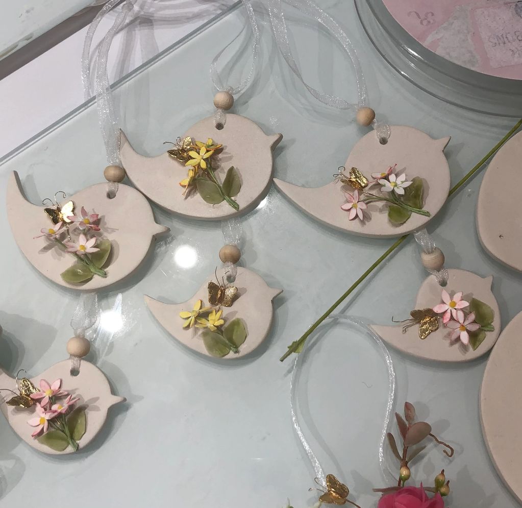 Clay bird ornaments with flowers and golden butterflies.