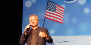 Gary Sinise speaking onstage during a military-support event