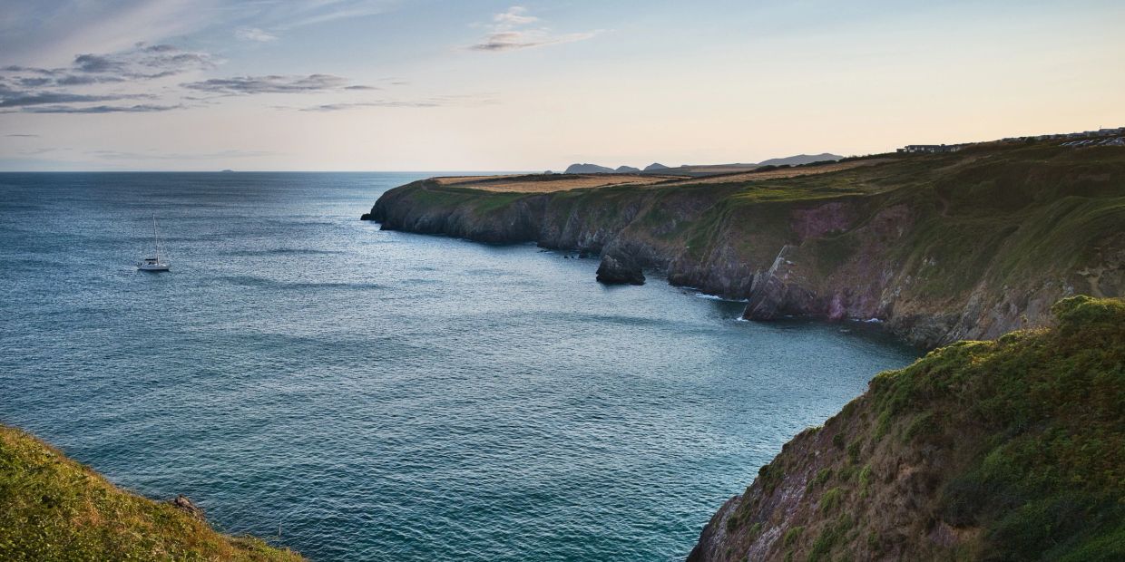 Scenic coastline with cliffs and a boat on the water.