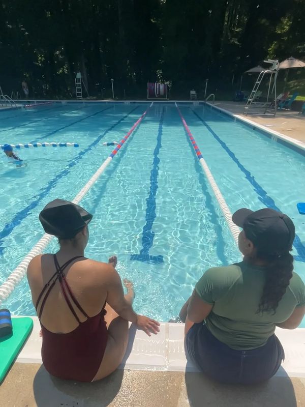 Two women sitting by the poolside on a sunny day.