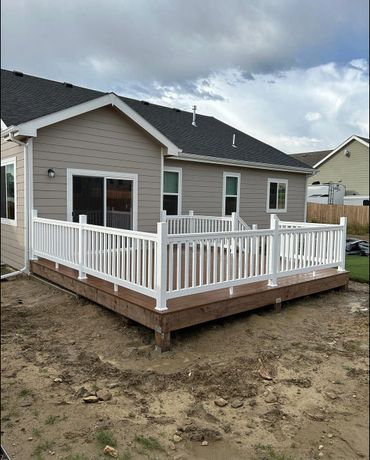 Newly built wooden deck with white railing attached to a house.