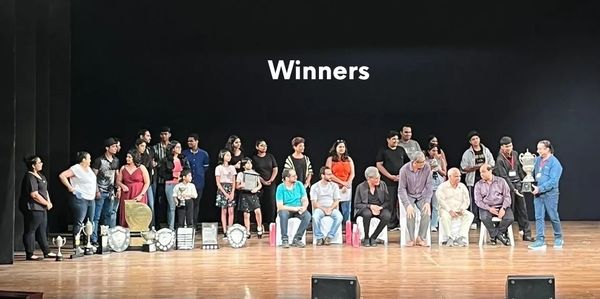 Group of winners posing on stage with trophies.