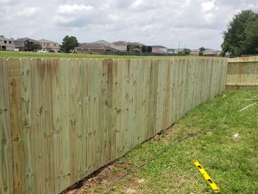 Newly installed wooden privacy fence in suburban backyard.