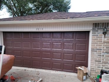 Brown garage door with house number 2814 and some clutter in front.