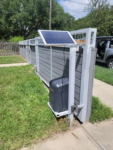 Solar panel powering an automatic gate opener on a sunny day.