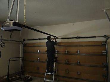Man repairing a garage door opener mechanism.