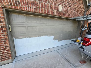 A garage door being painted from white to gray.