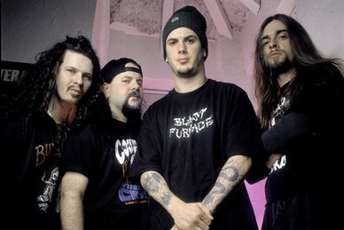 Four men posing with serious expressions and dark clothing.