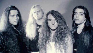 Black and white photo of four men with long hair.
