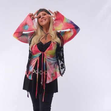 Woman posing with peace signs wearing a colorful tie-dye top and black skirt.